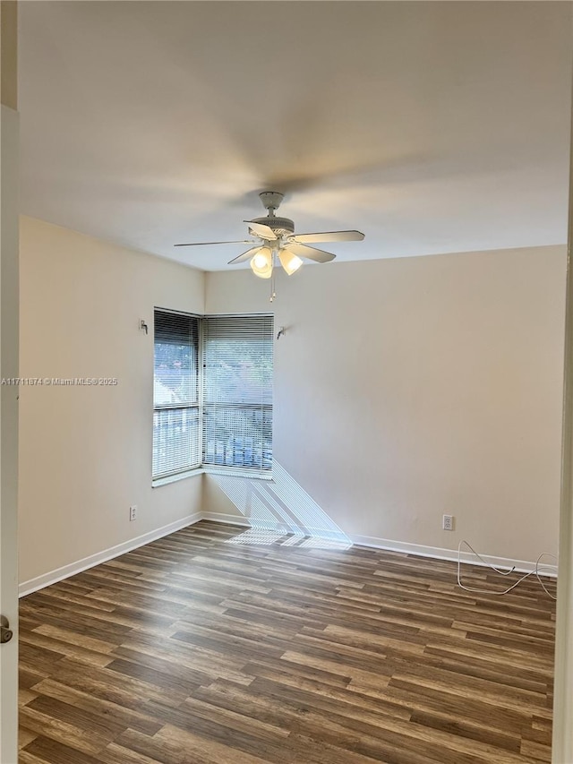 empty room featuring dark wood-style floors, baseboards, and a ceiling fan