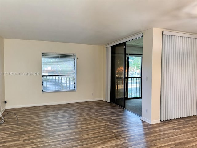 spare room with dark wood-type flooring and baseboards