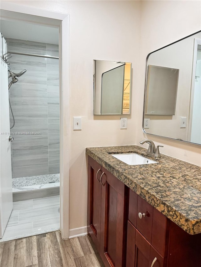 full bathroom with a stall shower, wood finished floors, vanity, and baseboards