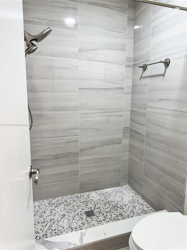 bathroom featuring tiled shower and toilet