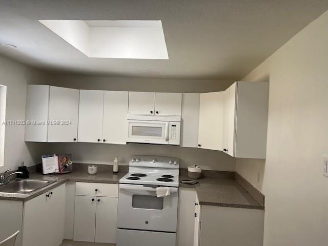 kitchen featuring white appliances, white cabinetry, and sink