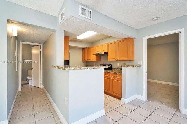 kitchen featuring light stone countertops, a textured ceiling, and light tile patterned floors