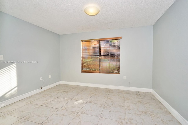 unfurnished room with a textured ceiling