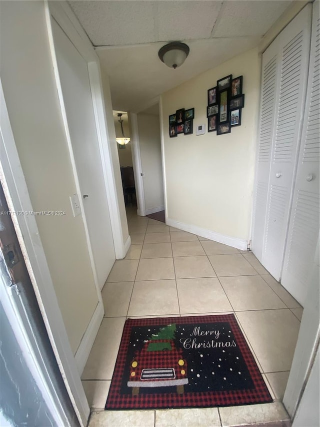 corridor with light tile patterned floors and a paneled ceiling