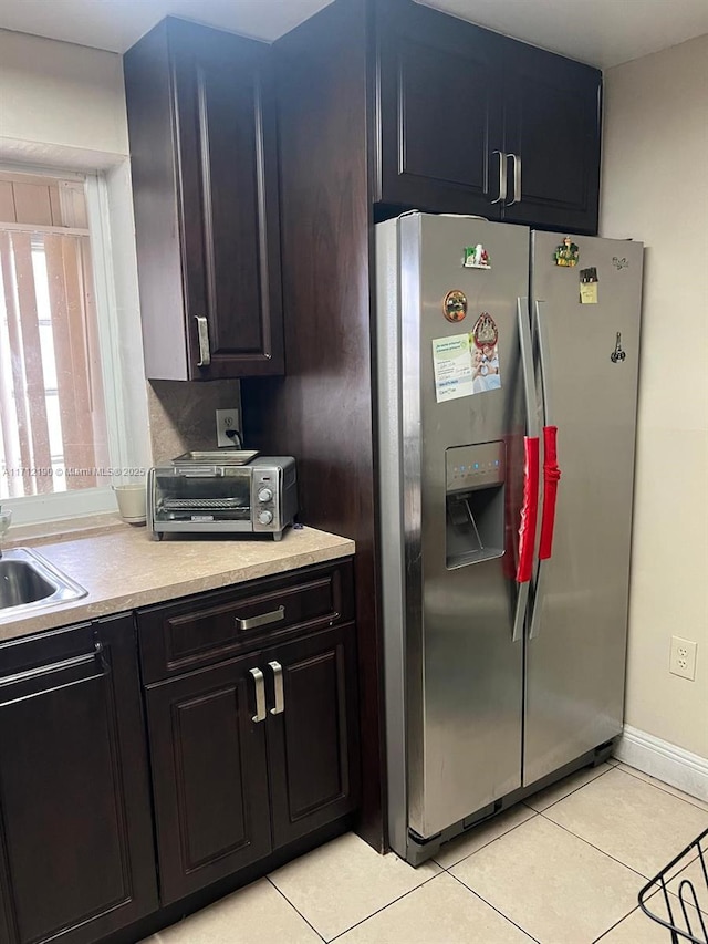 kitchen with stainless steel refrigerator with ice dispenser, sink, and light tile patterned floors