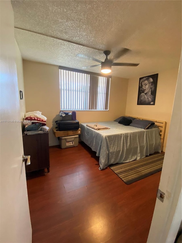 bedroom with a textured ceiling, dark wood-type flooring, and ceiling fan