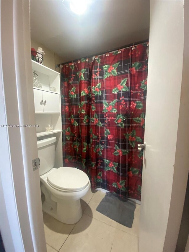 bathroom featuring tile patterned flooring, curtained shower, and toilet