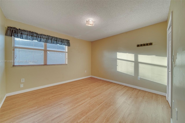 spare room featuring a textured ceiling and light hardwood / wood-style floors