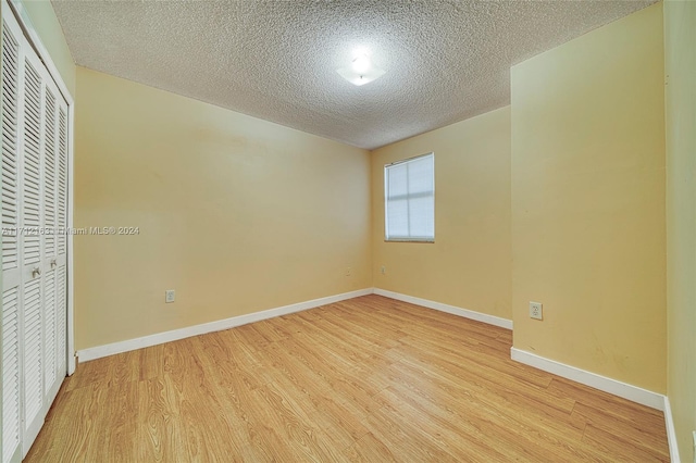 unfurnished bedroom featuring light hardwood / wood-style floors, a textured ceiling, and a closet