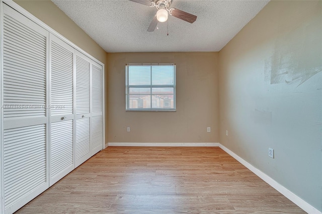 unfurnished bedroom featuring light wood-type flooring, a textured ceiling, a closet, and ceiling fan