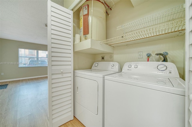 laundry room featuring washing machine and dryer, light hardwood / wood-style floors, and a textured ceiling