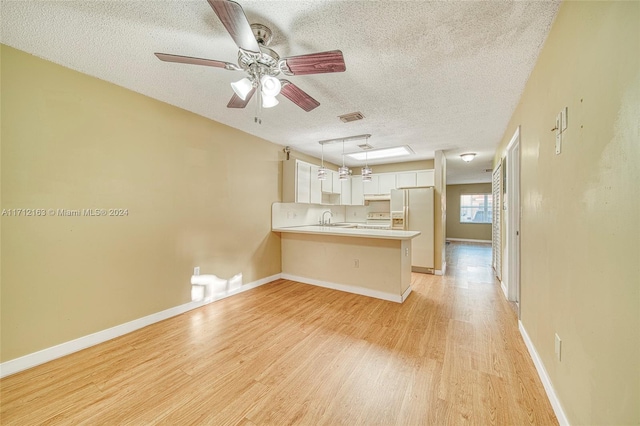 unfurnished living room with ceiling fan, light hardwood / wood-style floors, sink, and a textured ceiling