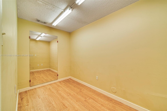 empty room with a textured ceiling and hardwood / wood-style flooring