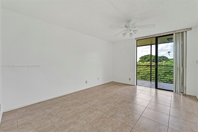 tiled spare room with a textured ceiling, expansive windows, and ceiling fan