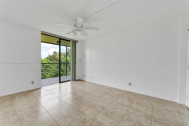 tiled empty room featuring a textured ceiling, expansive windows, and ceiling fan