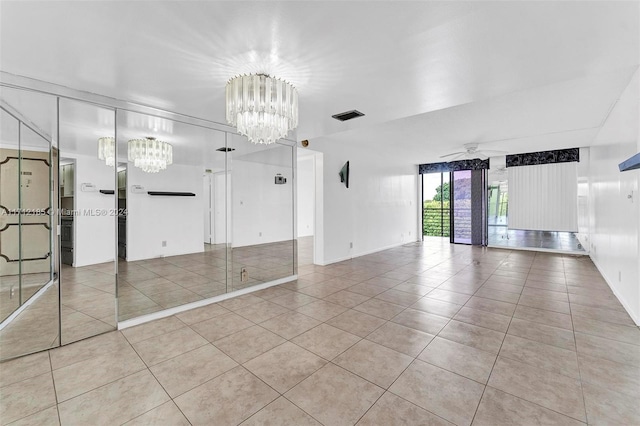 spare room with ceiling fan with notable chandelier and light tile patterned flooring