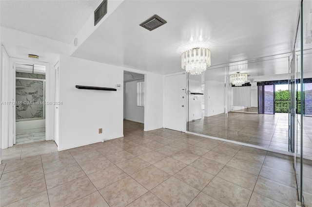 tiled empty room with an inviting chandelier