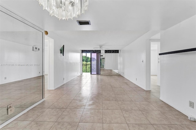 spare room with ceiling fan with notable chandelier and light tile patterned flooring