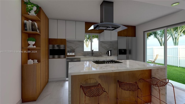 kitchen with island exhaust hood, appliances with stainless steel finishes, tasteful backsplash, white cabinets, and a center island