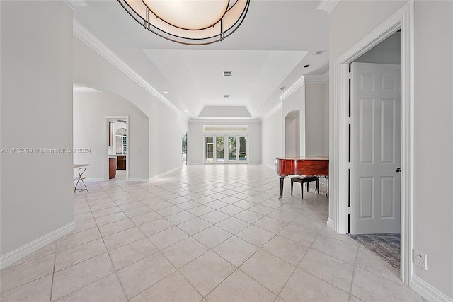 hallway featuring ornamental molding, light tile patterned floors, and a tray ceiling