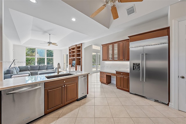 kitchen with a tray ceiling, sink, a healthy amount of sunlight, and appliances with stainless steel finishes