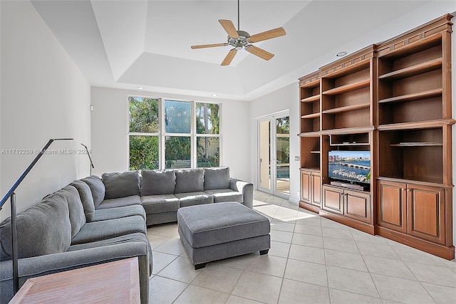 living room featuring ceiling fan, a raised ceiling, and light tile patterned floors