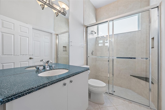 bathroom featuring tile patterned floors, vanity, a shower with shower door, and toilet