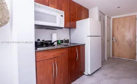 kitchen featuring stone countertops, white appliances, and sink