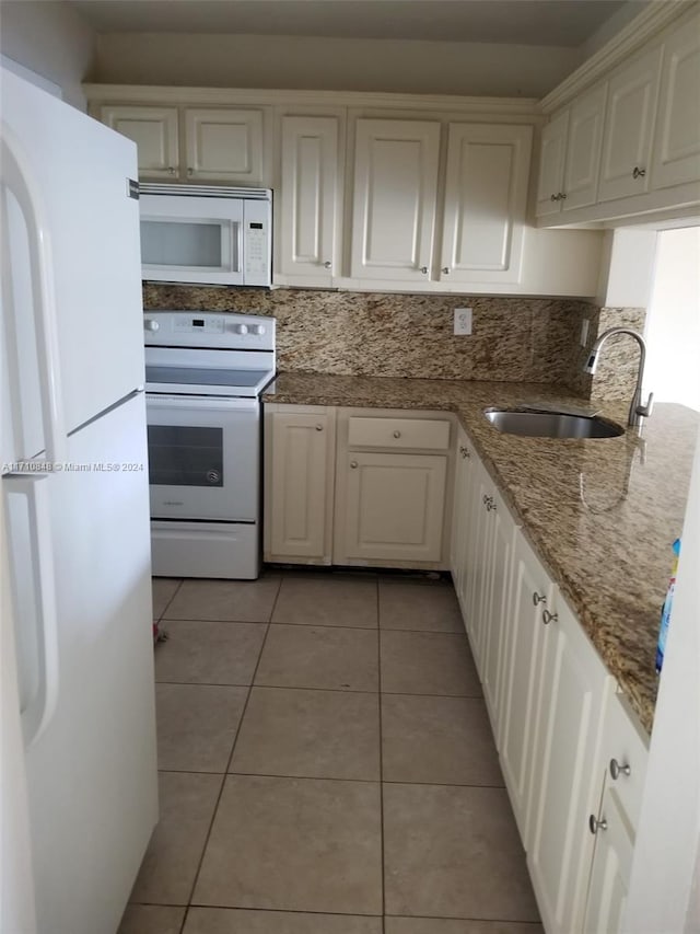 kitchen with white cabinetry, sink, light stone countertops, white appliances, and light tile patterned floors