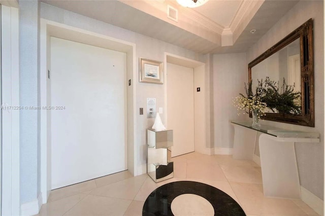 bathroom with a raised ceiling, elevator, crown molding, and tile patterned flooring