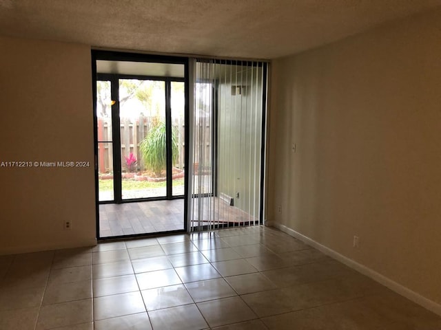 unfurnished room featuring light tile patterned floors, a textured ceiling, and a wealth of natural light