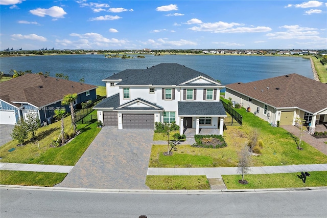 view of front of home featuring a water view, covered porch, a front yard, and a garage