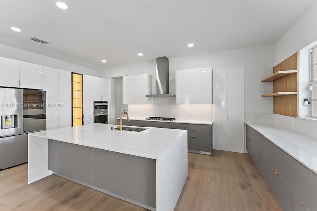 kitchen featuring white cabinets, sink, and wall chimney range hood