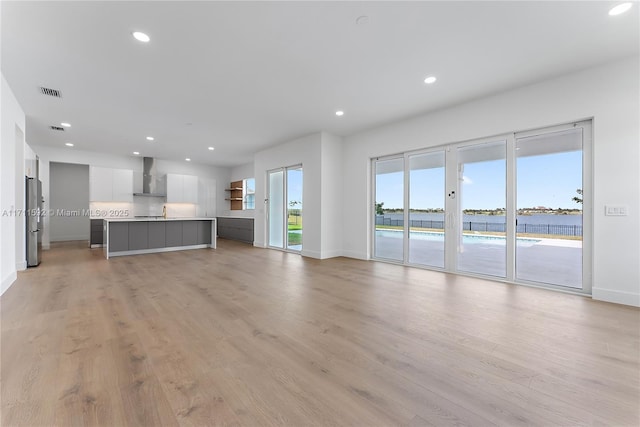 unfurnished living room with a water view and light hardwood / wood-style flooring