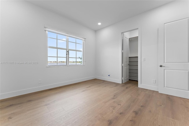 unfurnished bedroom with light hardwood / wood-style floors and a walk in closet