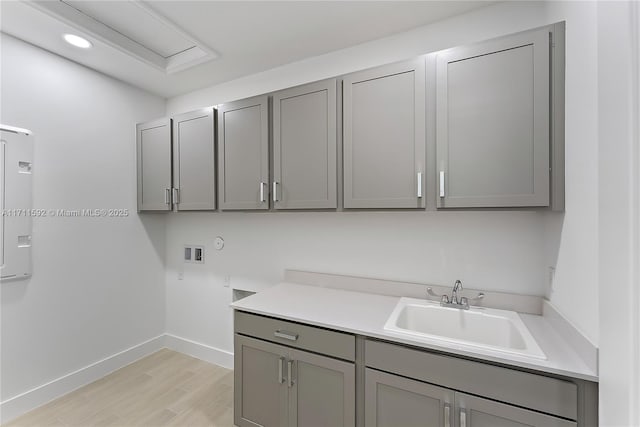 washroom featuring hookup for a washing machine, sink, cabinets, and light hardwood / wood-style floors