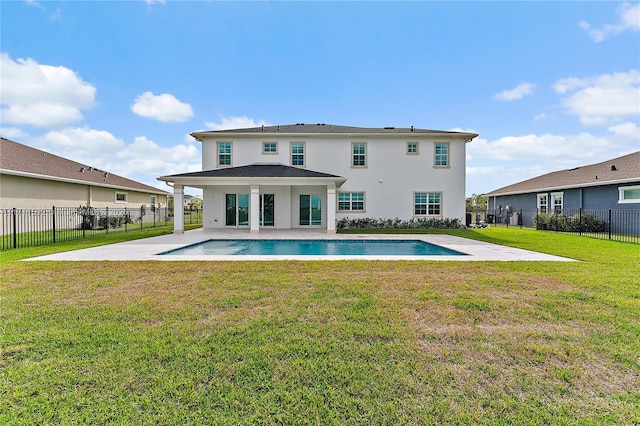 back of property with a fenced in pool, a yard, and a patio