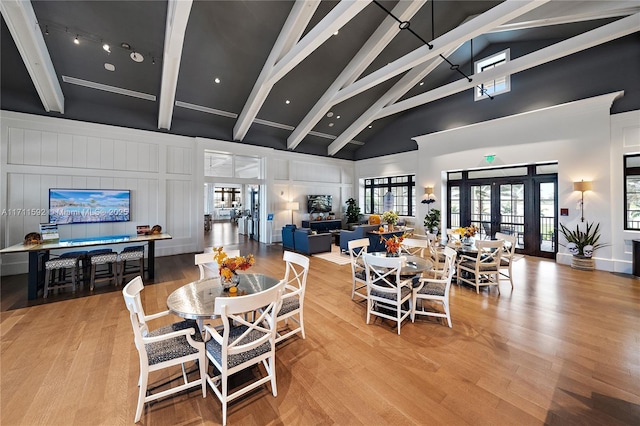 dining area with light hardwood / wood-style flooring, beam ceiling, and french doors