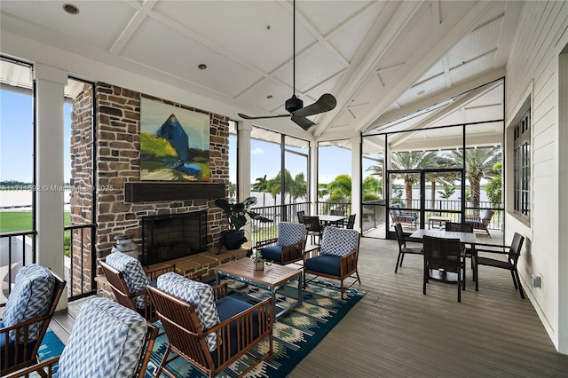 sunroom / solarium featuring a stone fireplace, plenty of natural light, and ceiling fan