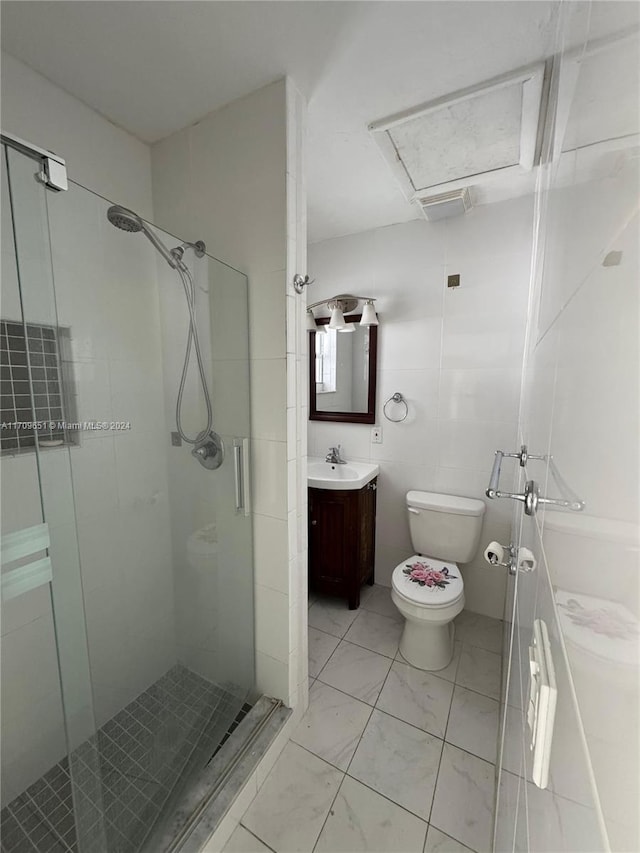 bathroom with vanity, toilet, a shower with door, and tile walls