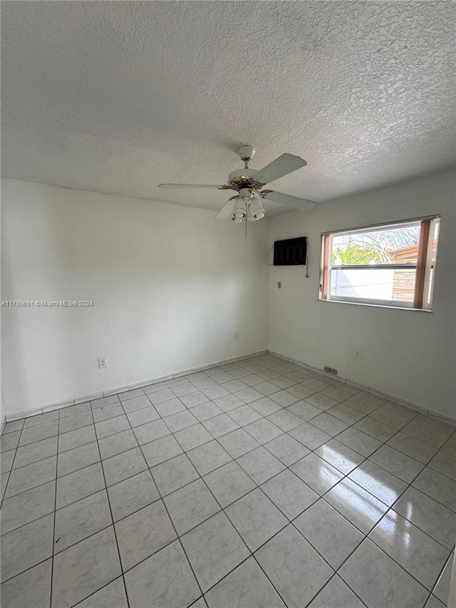 unfurnished room with ceiling fan, light tile patterned flooring, and a textured ceiling