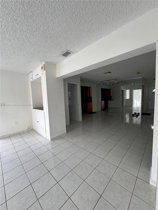 tiled spare room with a textured ceiling