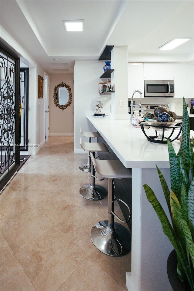 kitchen with white cabinets, a breakfast bar, and kitchen peninsula