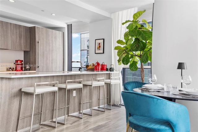 kitchen with a kitchen breakfast bar, kitchen peninsula, light hardwood / wood-style flooring, and sink