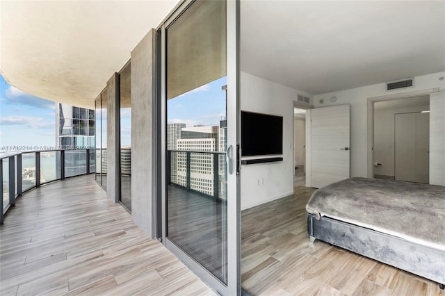 bedroom featuring expansive windows and light hardwood / wood-style floors