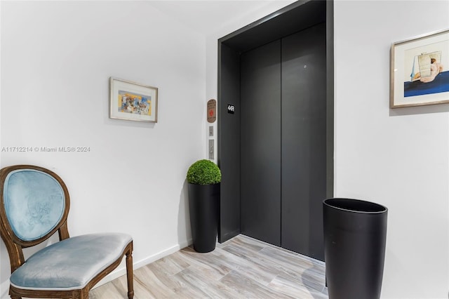 hallway with elevator and light hardwood / wood-style floors