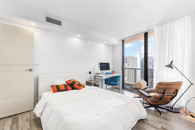 bedroom featuring light hardwood / wood-style floors and a wall of windows