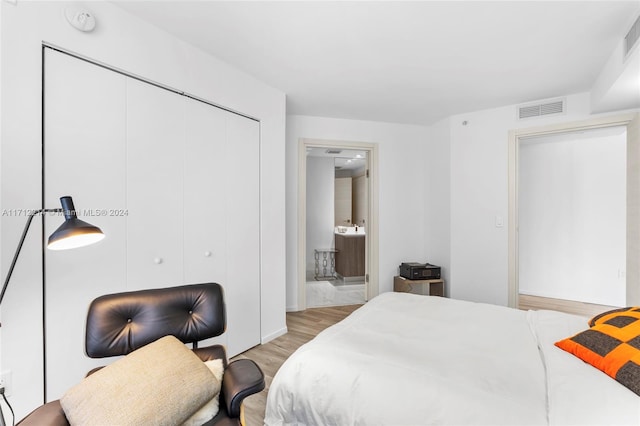 bedroom with ensuite bath, a closet, and light hardwood / wood-style floors