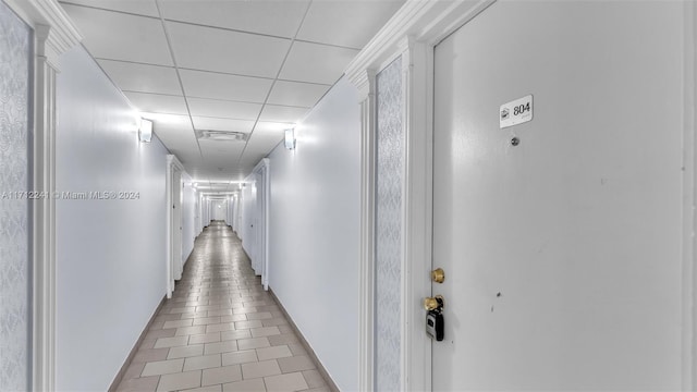 corridor featuring a drop ceiling and light tile patterned floors