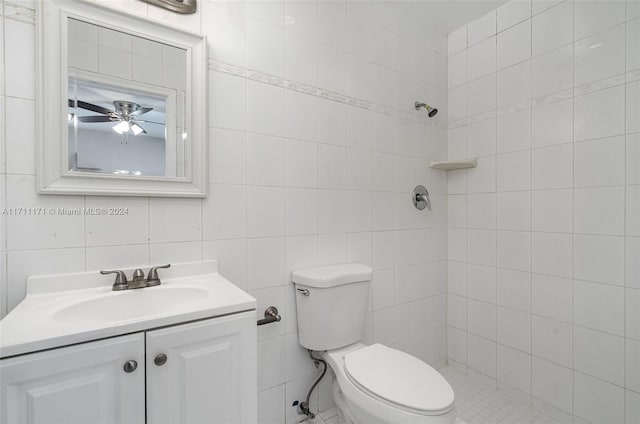 bathroom with vanity, ceiling fan, toilet, tile walls, and a tile shower